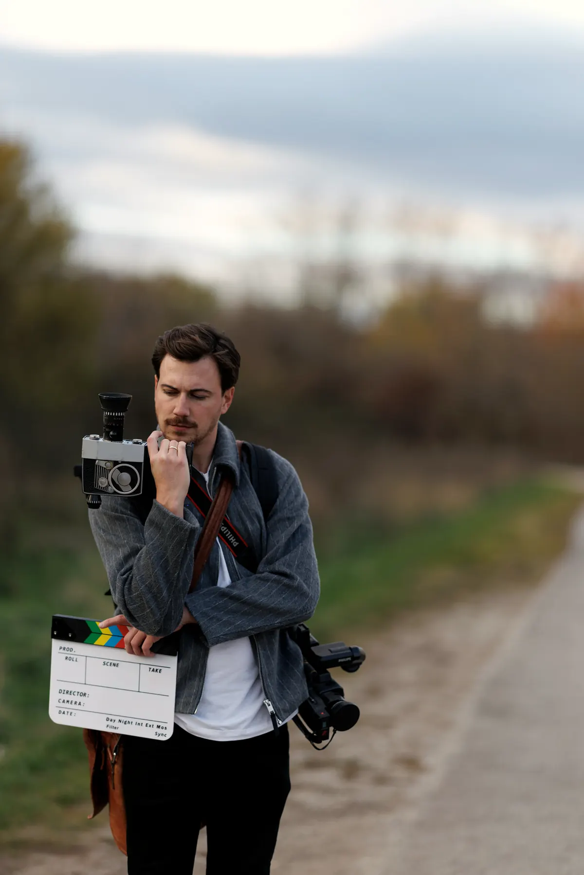 Pascal mit Filmkamera und Klappe auf einer Landstraße
